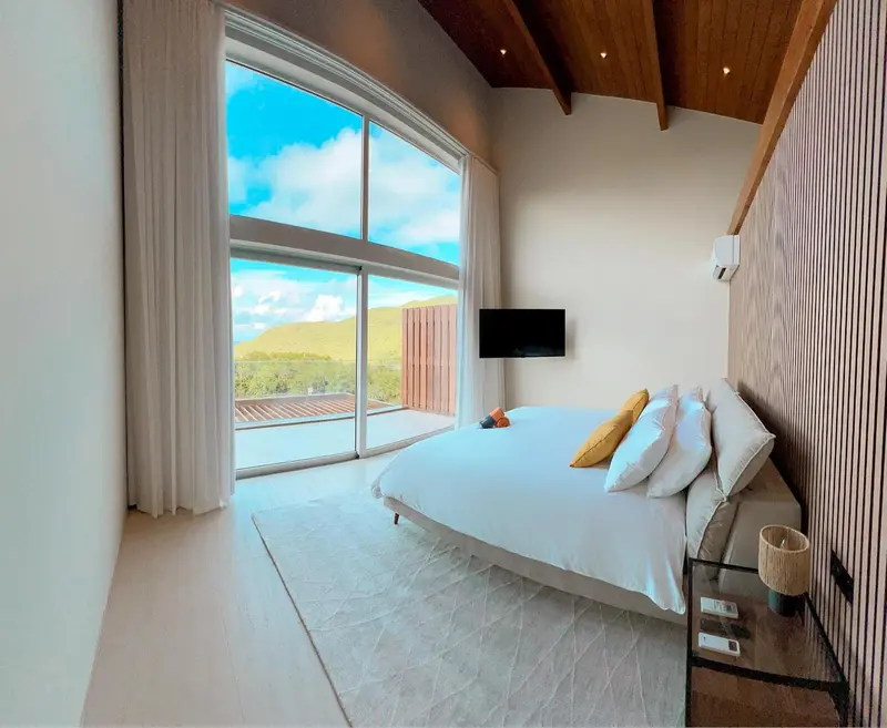 Une chambre lumineuse avec un grand lit et une vue sur un paysage verdoyant.