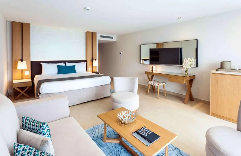 Une chambre lumineuse avec un grand lit et un espace salon.