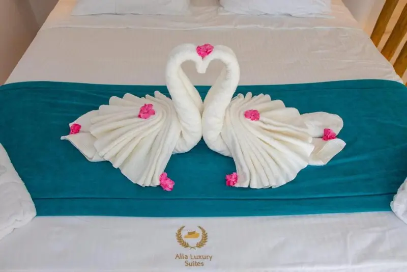 Un lit soigneusement fait avec des serviettes pliées en forme de cygnes.