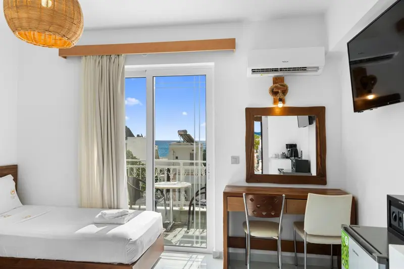 Une chambre lumineuse avec un lit et un bureau donnant sur une vue mer.