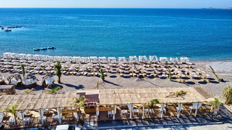 Vue aérienne d'une plage avec des transats et des parasols.