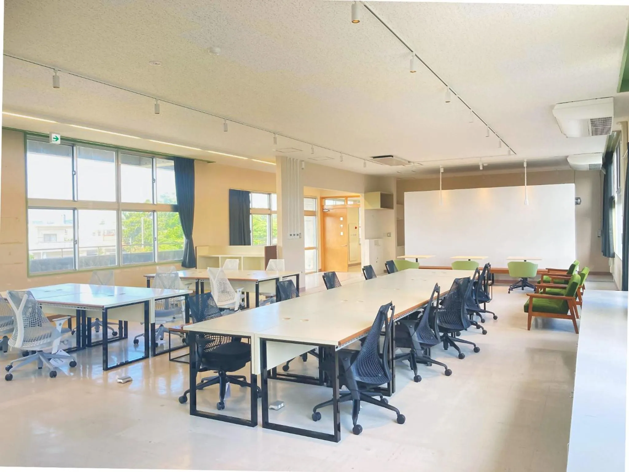 Une grande salle lumineuse est aménagée avec des tables et des chaises.