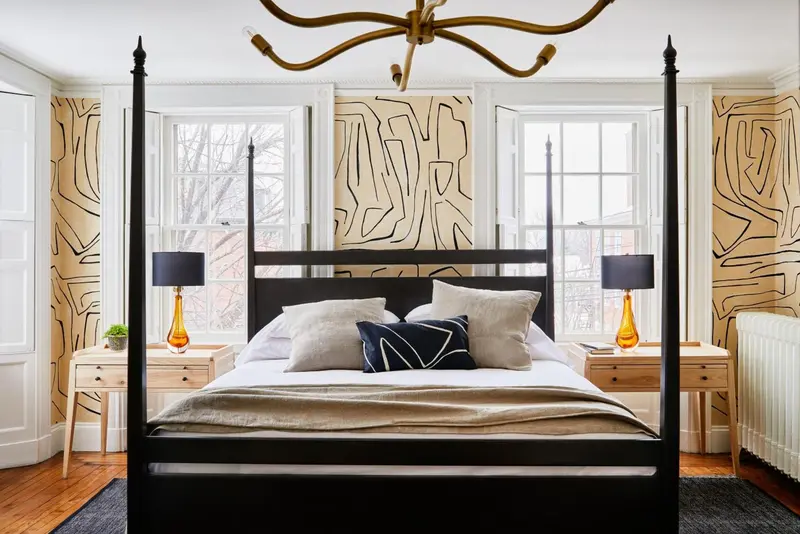 Un lit à baldaquin en bois sombre se trouve dans une chambre décorée de papier peint.