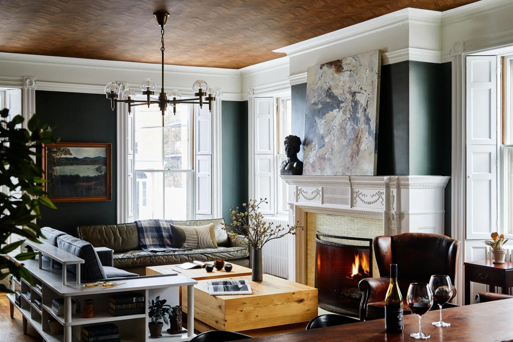 Un salon chaleureux avec un canapé vert, une cheminée et des fauteuils en cuir.