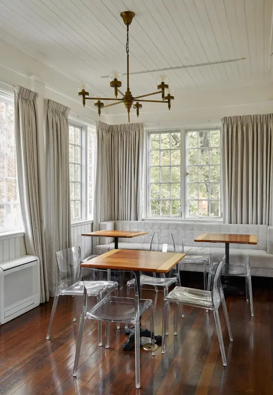 Une salle lumineuse avec des tables et des banquettes près de fenêtres.