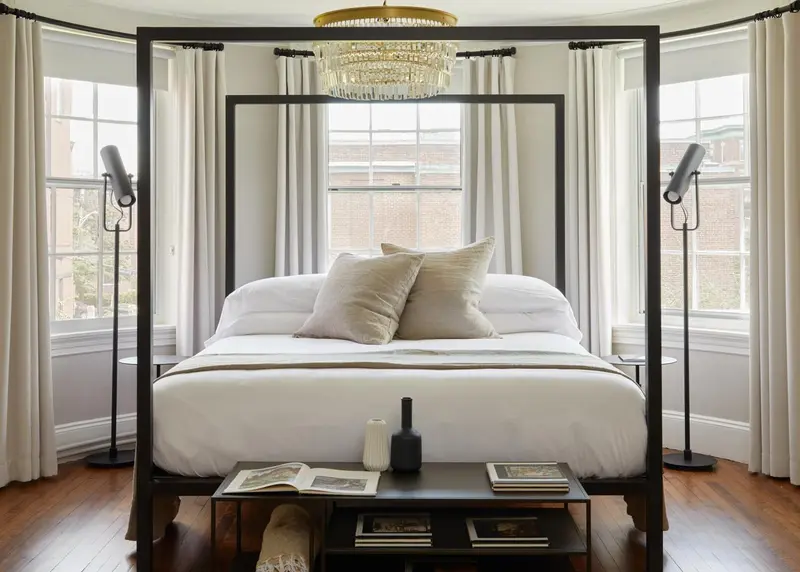 Un grand lit à baldaquin blanc est installé dans une chambre lumineuse.