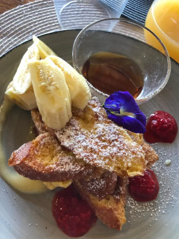 Assiette de pain perdu garnie de fruits et de confiture.