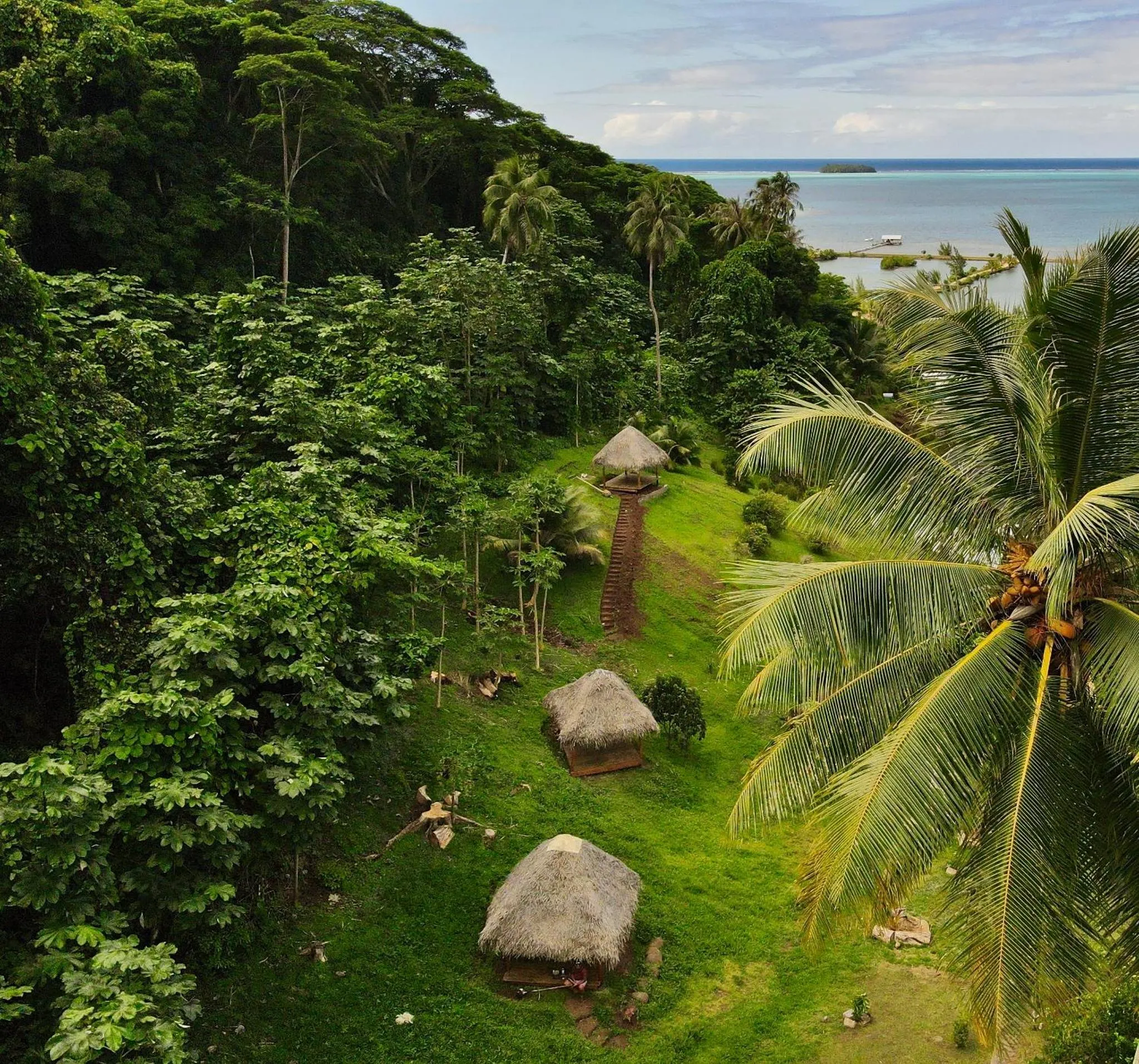 Des bungalows traditionnels s'intègrent dans une végétation luxuriante avec vue sur la mer.