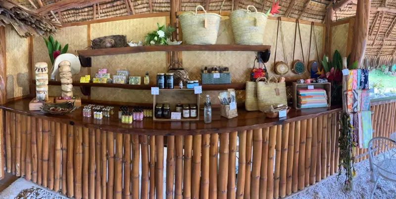 Un comptoir en bois et bambou expose des produits artisanaux et des articles de toilette.