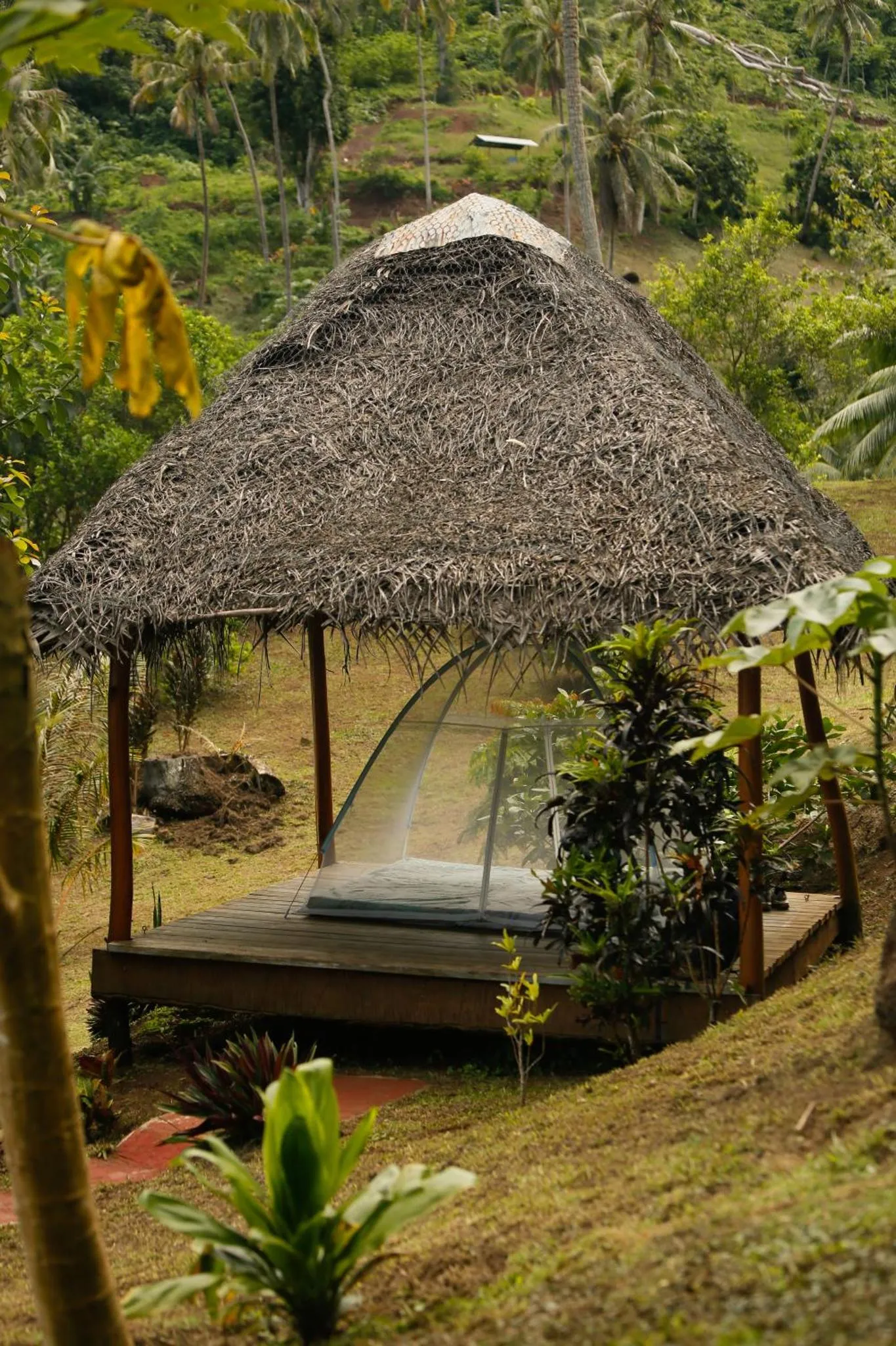 Un pavillon de chaume abrite un espace de détente sur une terrasse en bois.