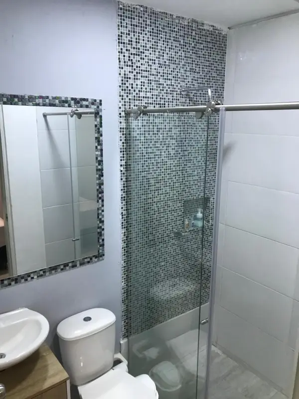 Une salle de bain claire avec douche à l'italienne et miroir.
