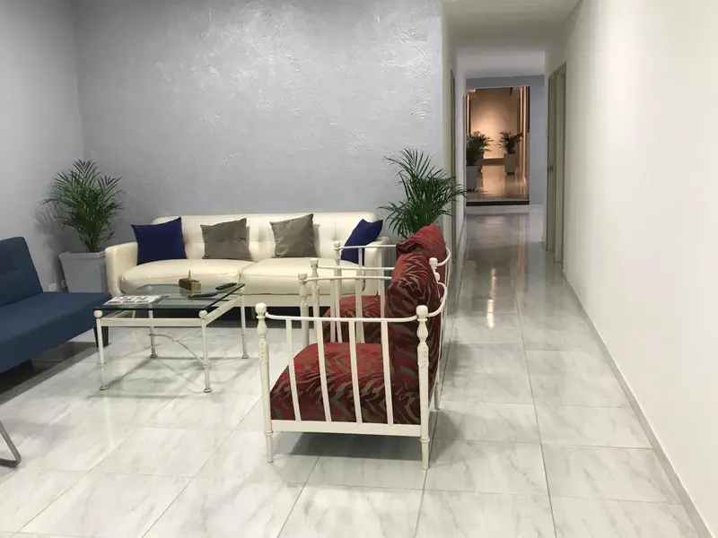 Un salon clair avec canapés et fauteuils.