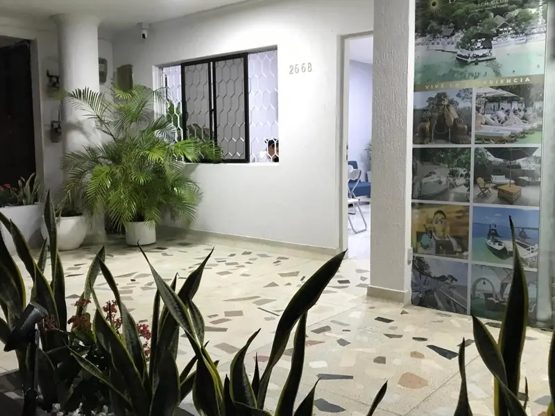 Un hall d'entrée lumineux avec un sol à motifs et des plantes vertes.