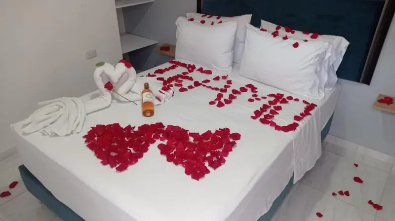 Lit décoré de pétales de fleurs et de serviettes en forme de cœur.