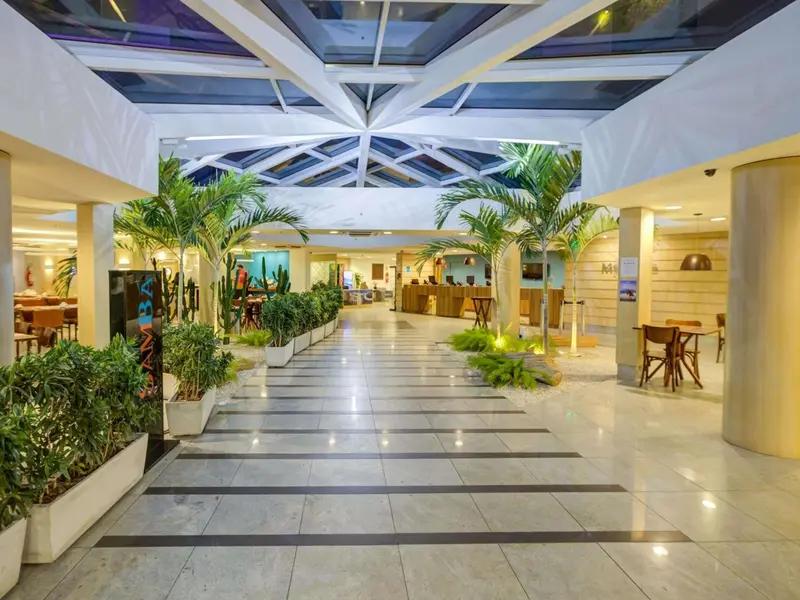 Vaste hall d'accueil avec plantes tropicales et sol carrelé.