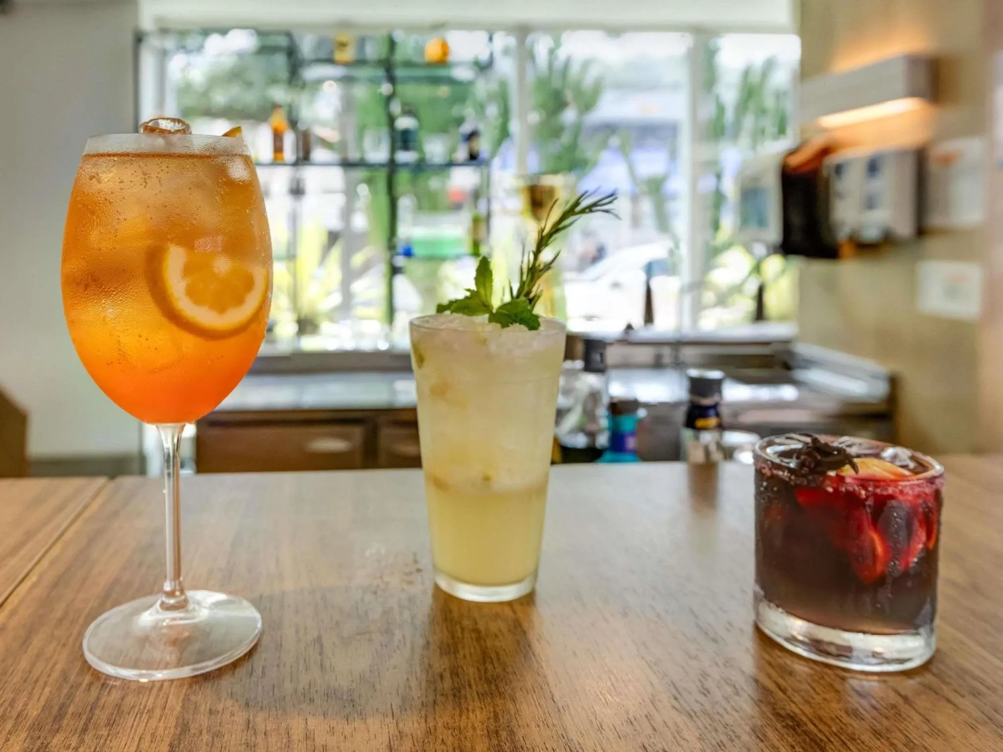 Trois boissons colorées sur un comptoir en bois.
