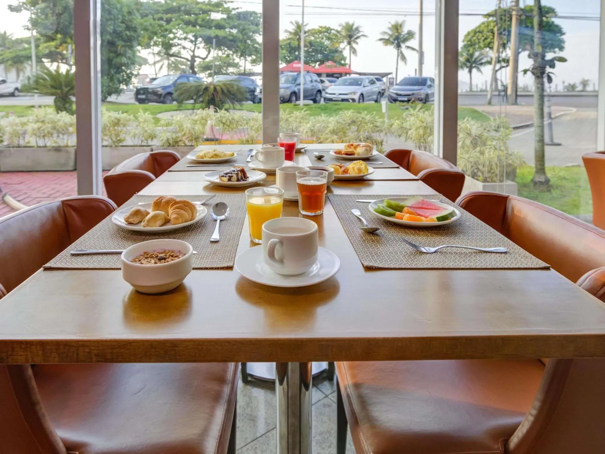 Une table est dressée pour le petit-déjeuner avec des viennoiseries, des fruits et des boissons.