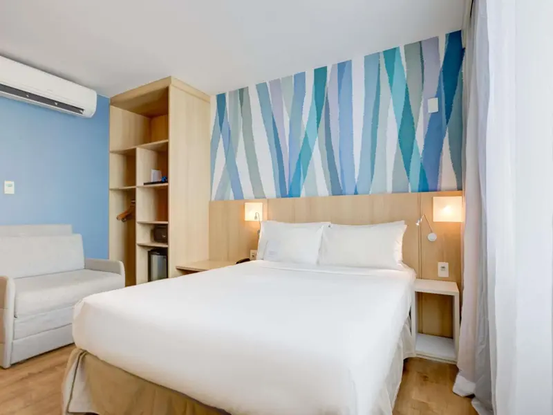 Une chambre lumineuse avec un lit double et un canapé.