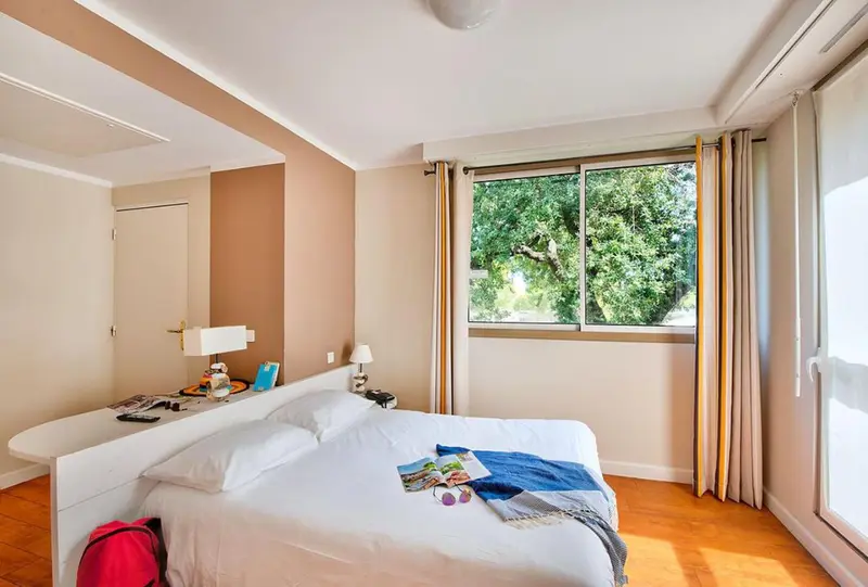 Une chambre lumineuse avec un grand lit et une vue sur la végétation.