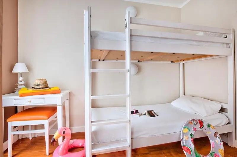 Une chambre avec un lit superposé et un lit simple.