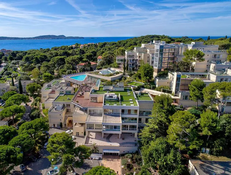 Vue aérienne d'un complexe hôtelier avec piscine et végétation luxuriante.
