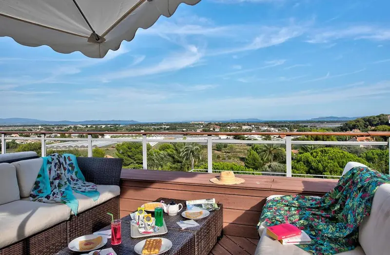Une terrasse aménagée offre une vue dégagée sur un paysage verdoyant et la mer.