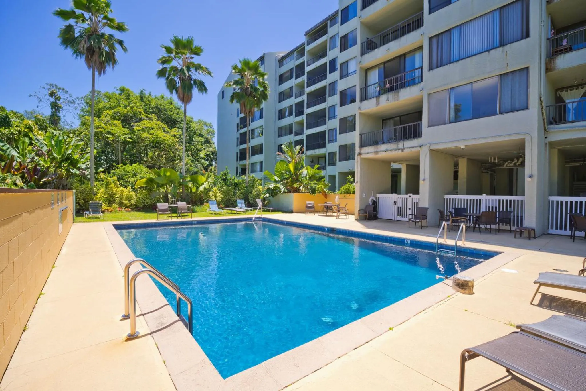 Une piscine rectangulaire entourée d'une terrasse ensoleillée avec des transats.