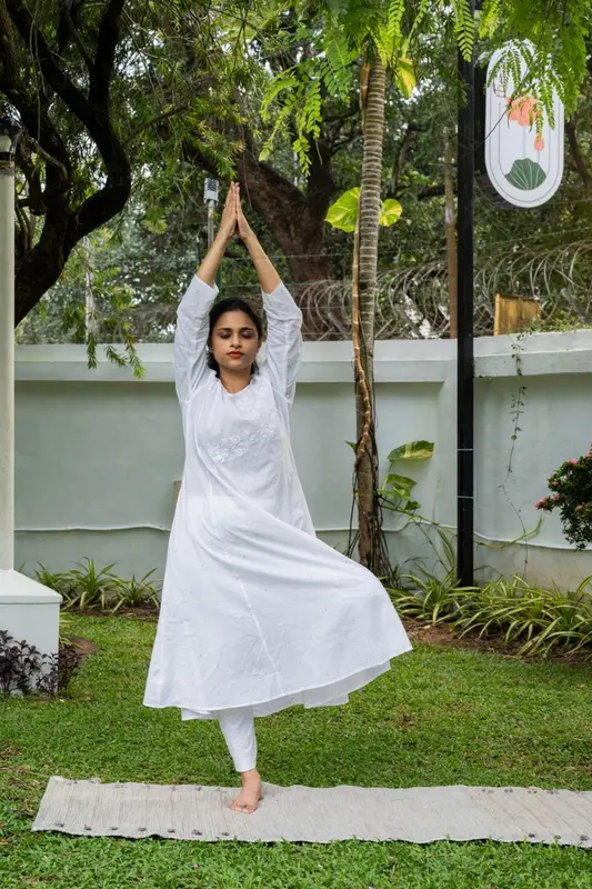 Une femme pratique le yoga sur une pelouse verdoyante.