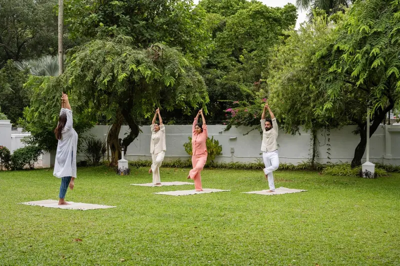 Quatre personnes pratiquent le yoga sur une pelouse verdoyante.