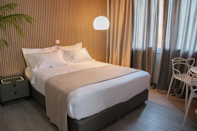 Une chambre avec un grand lit recouvert d'une couette blanche et de coussins.