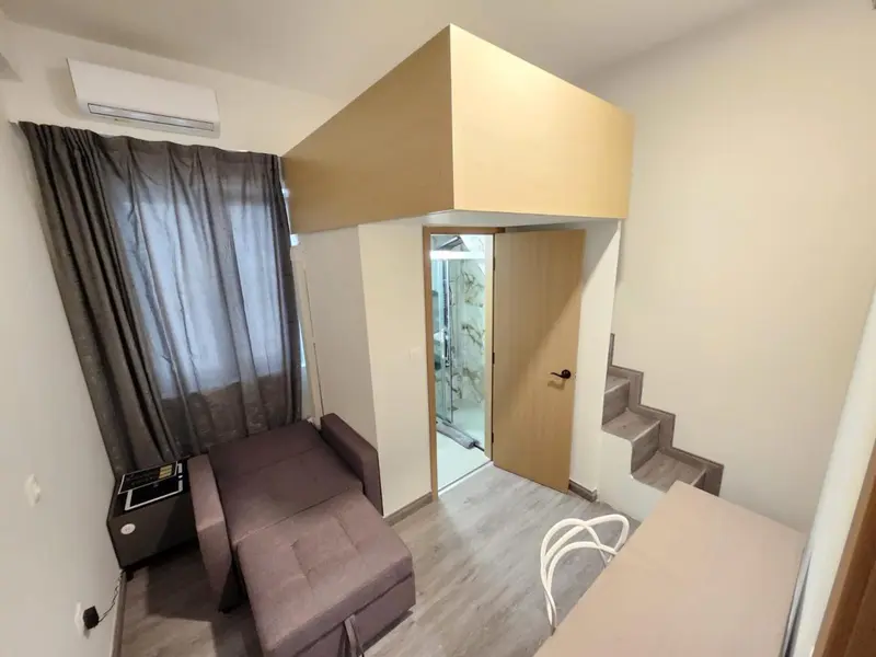 Une chambre avec un lit en mezzanine et un canapé près d'une fenêtre.