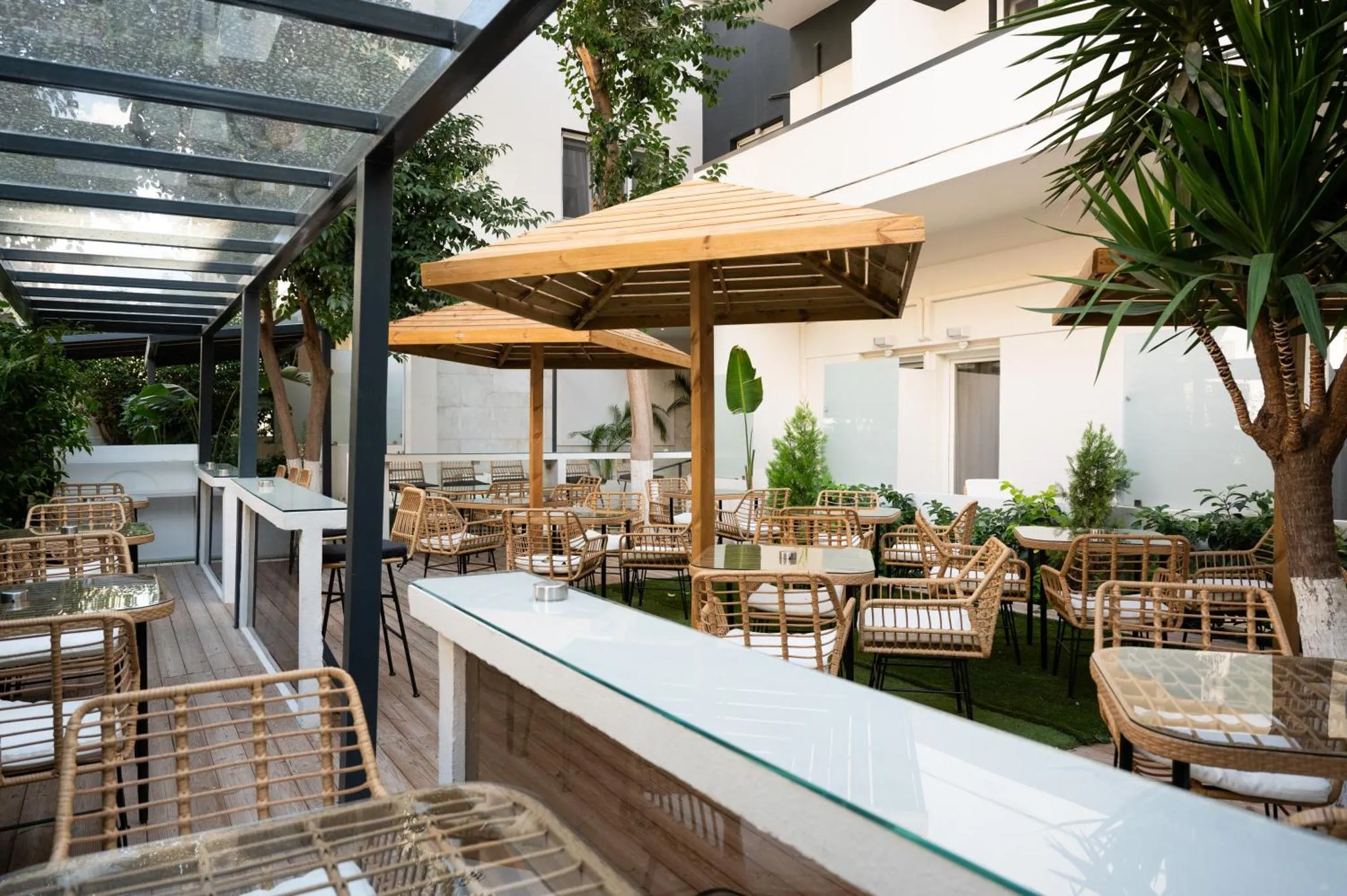 Terrasse ombragée avec tables et chaises en osier.