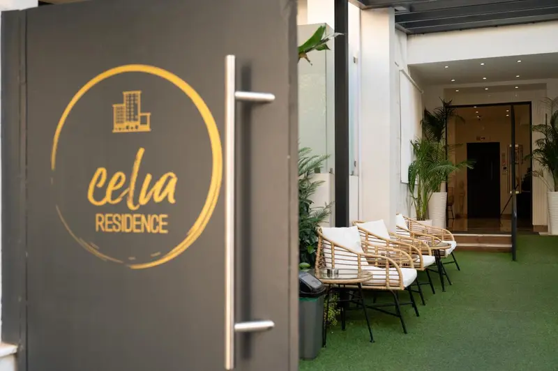 Entree d'une residence avec un logo circulaire et des fauteuils en osier.
