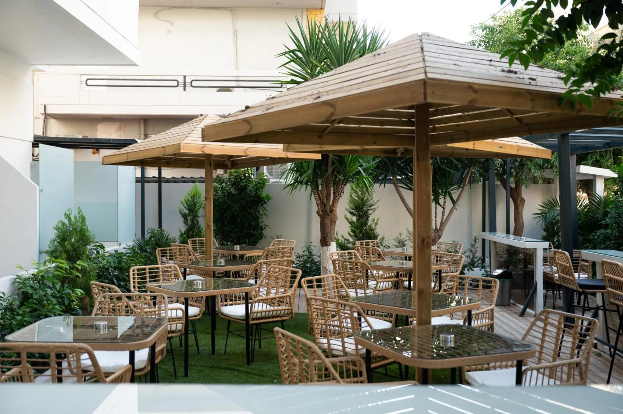 Terrasse ombragée avec tables et chaises en rotin.