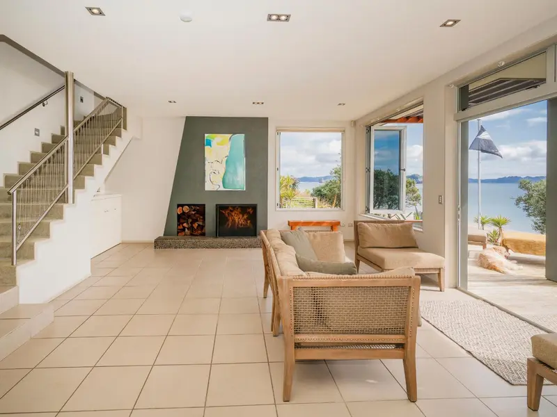 Espace de vie lumineux avec canapés et vue sur la mer par de grandes baies vitrées.