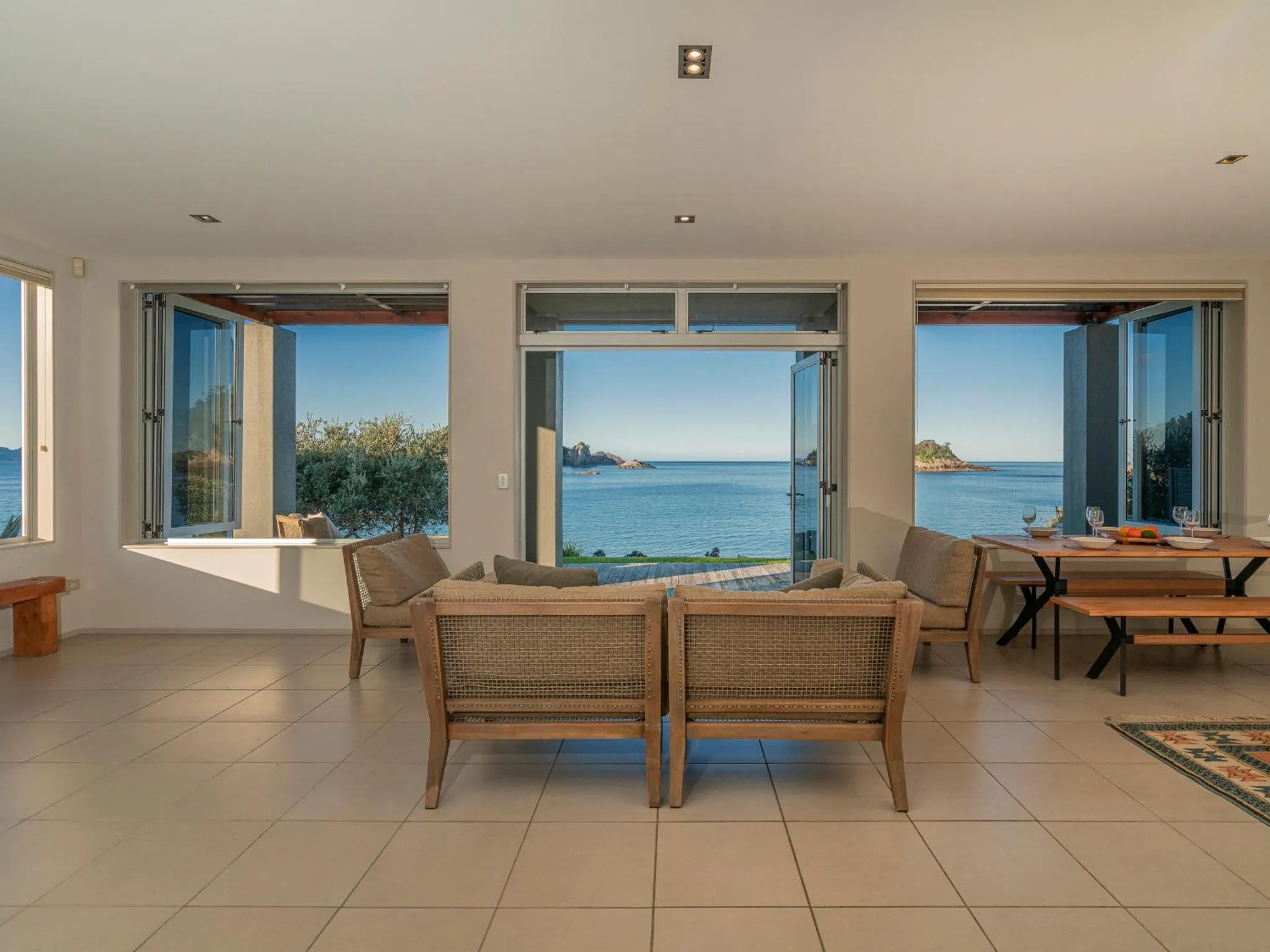 Espace de vie lumineux avec vue sur la mer à travers de grandes baies vitrées.