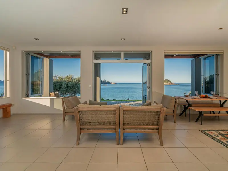 Espace de vie lumineux avec vue sur la mer à travers de grandes baies vitrées.