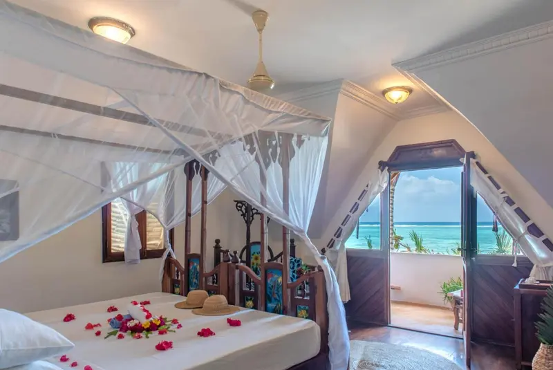 Une chambre à coucher lumineuse avec un lit à baldaquin donnant sur une vue sur la mer.