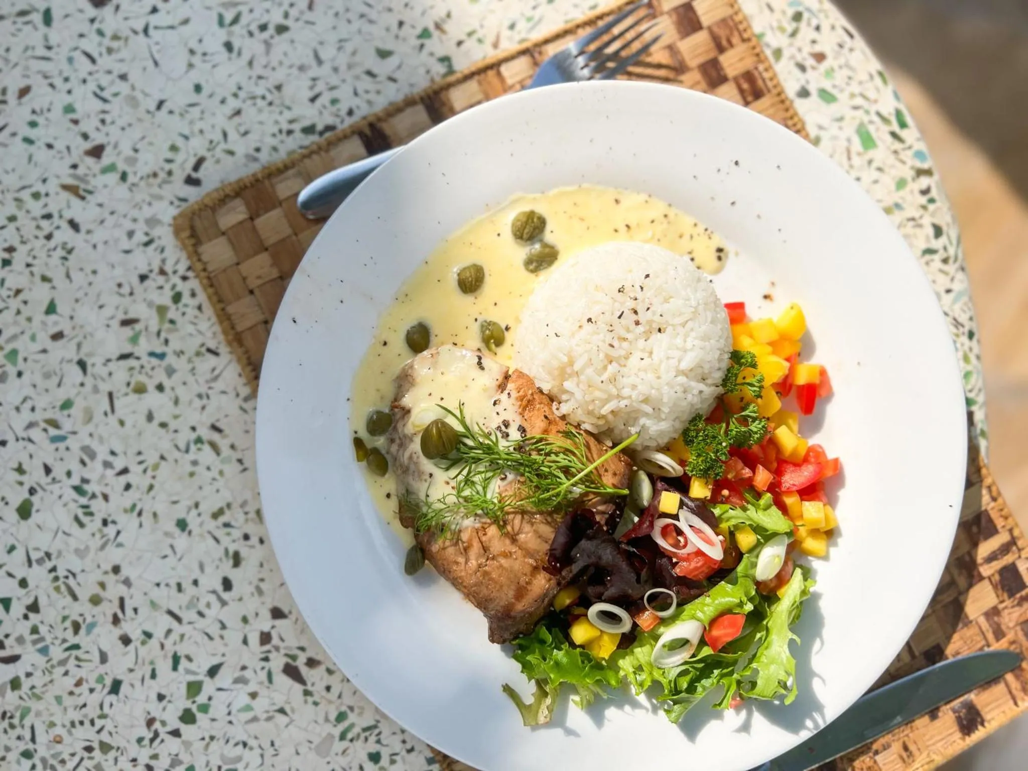 Assiette de poisson blanc, riz et légumes colorés.