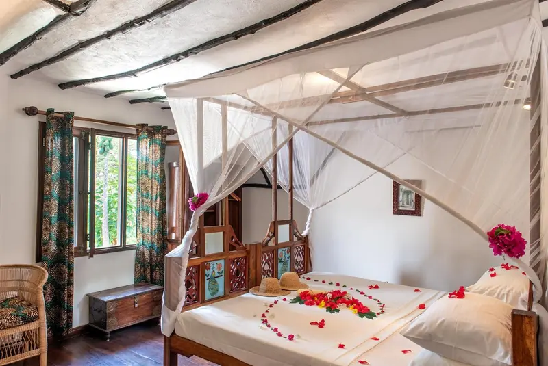 Une chambre décorée d'un lit à baldaquin et de fleurs.