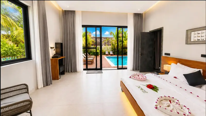 Une chambre lumineuse avec un grand lit et vue sur une piscine.