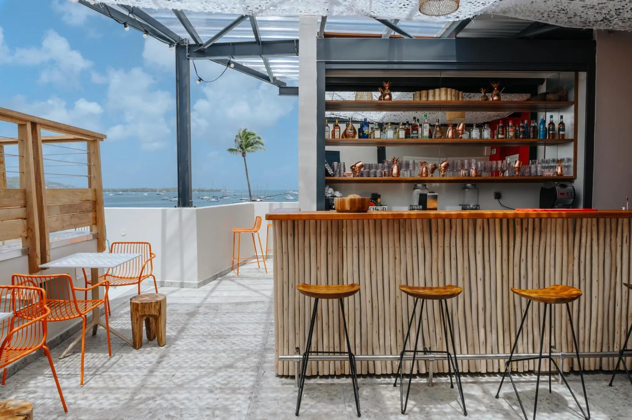 Un bar extérieur avec des tabourets et une vue sur la mer.