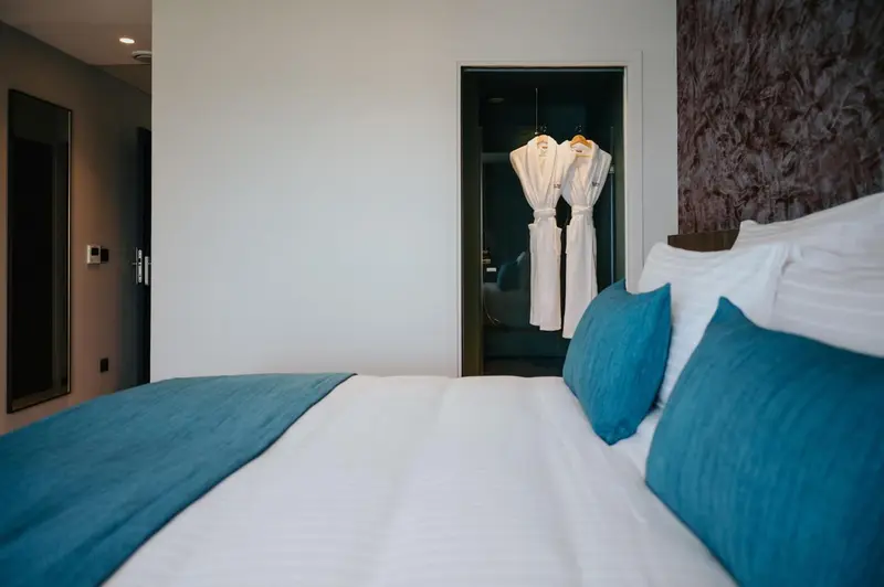 Un lit blanc avec des coussins turquoise dans une chambre d'hôtel.