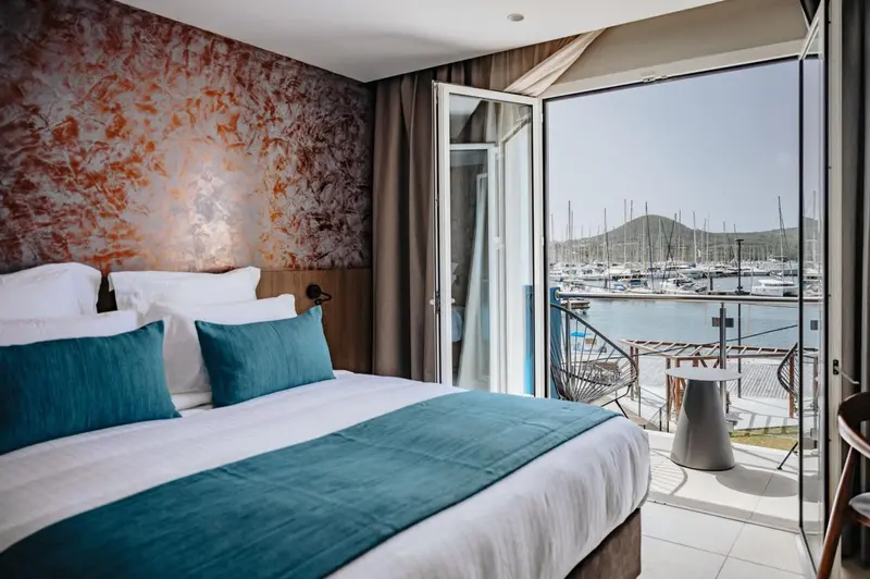 Une chambre avec un grand lit donnant sur une terrasse et un port de plaisance.