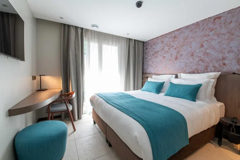 Une chambre d'hôtel moderne avec un lit turquoise et un bureau.