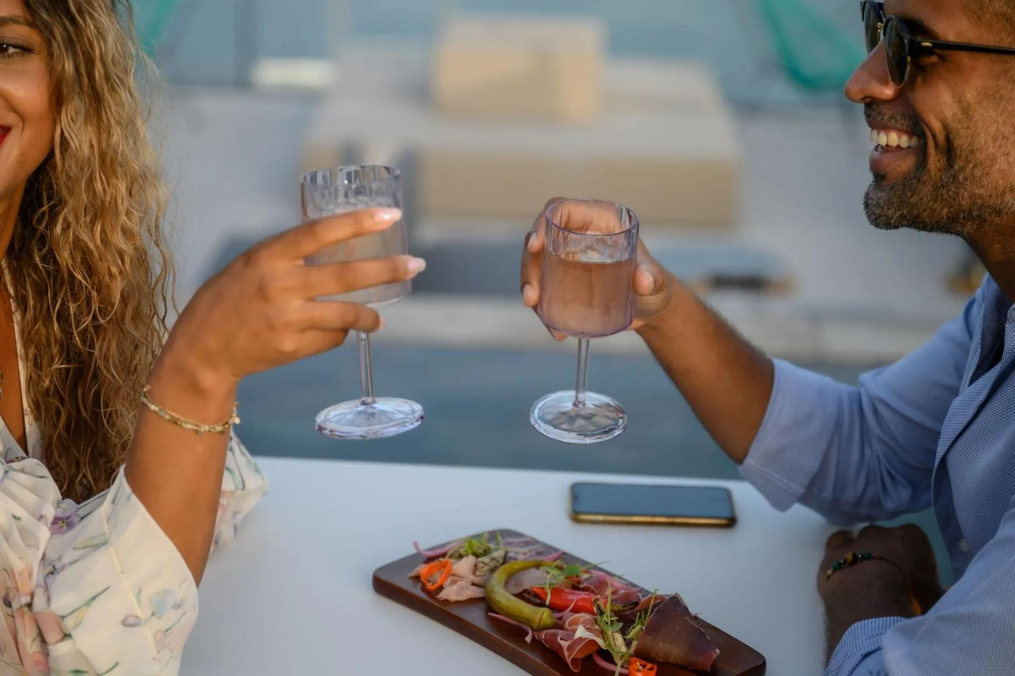 Deux personnes trinquent avec des verres sur une terrasse.