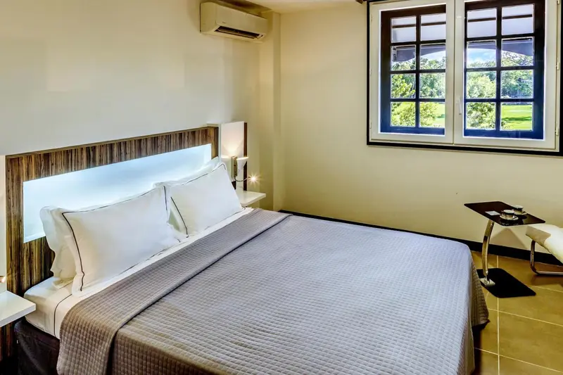Une chambre lumineuse avec un grand lit et une vue sur la végétation.