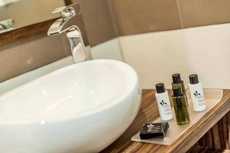 Un lavabo blanc avec des produits de toilette sur un meuble en bois.