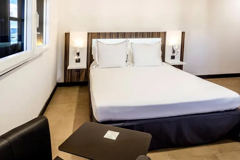 Une chambre lumineuse avec un grand lit recouvert d'une literie blanche.