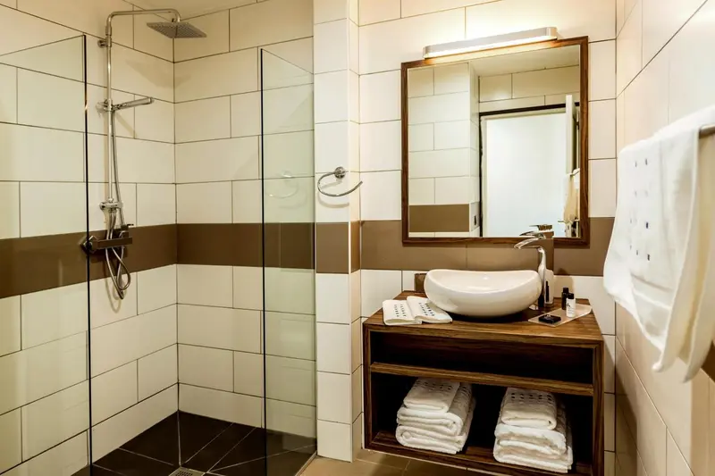 Une douche à l'italienne moderne avec un lavabo et des serviettes.